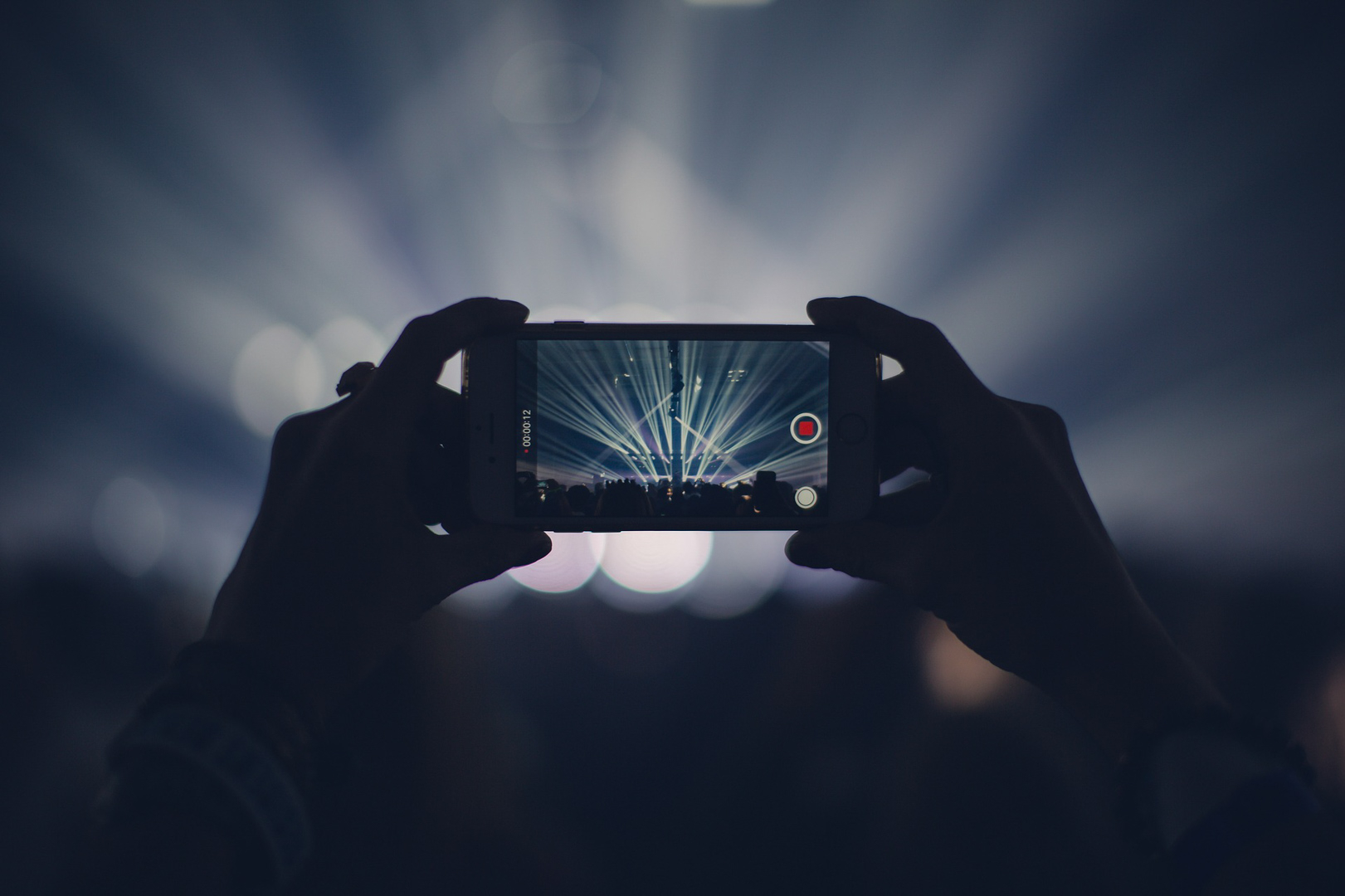 Eventfoto einer Konzertbühne mit Handy im Vordergrund
